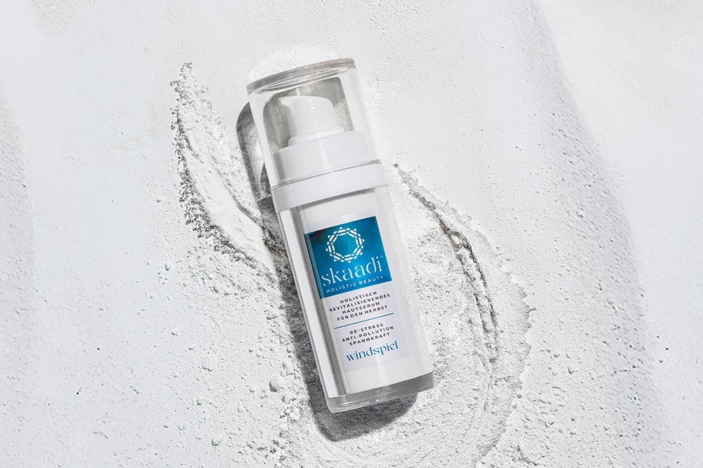 skaadi® Windspiel Elementra Herbstserum liegt auf weißem pudrigen Hintergrund