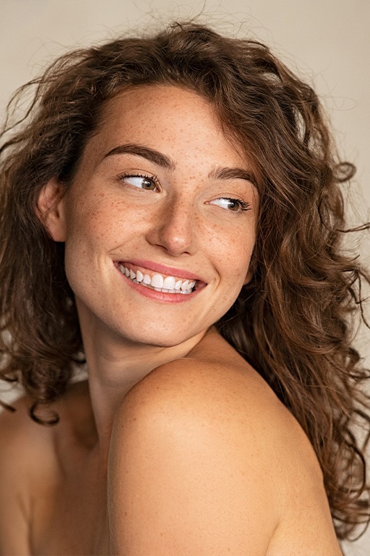 Glückliche lächelnde Frau mit Locken die zur Seite guckt